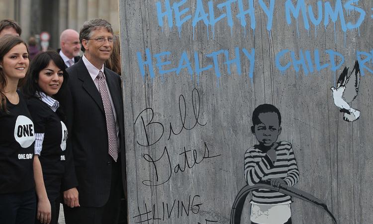 Bill Gates posa vicino a un murales