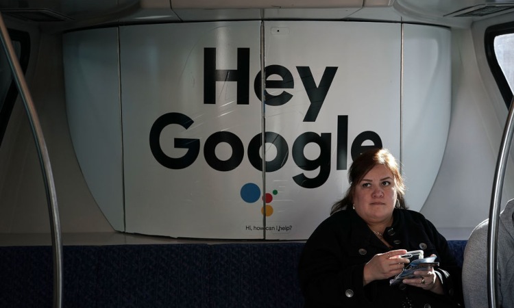 Una donna seduta vicino la scritta "Hey Google"