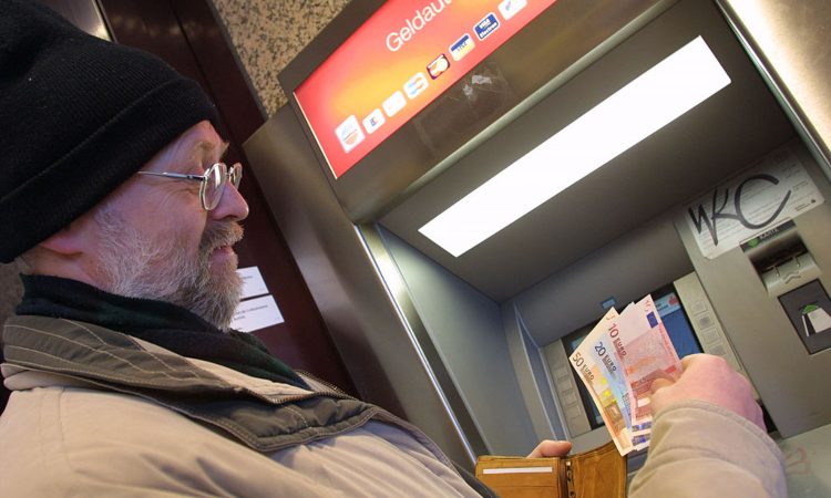 Un uomo mentre ritira delle banconote allo sportello automatico